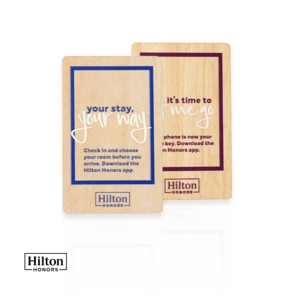 Two customized wooden hotel key cards featuring blue and purple designs alongside a Hilton Honors logo
