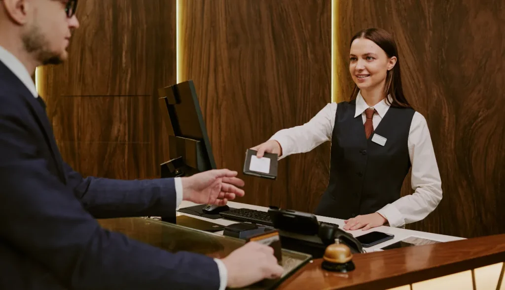 A hotel receptionist handing a key card to a guest during the check-in process.