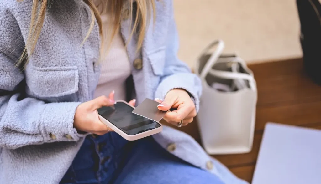 Person holding a smartphone and tapping an NFC card to interact with it.