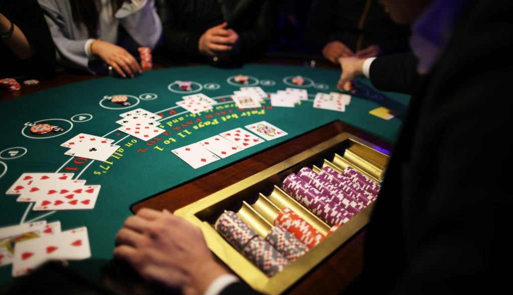 A blackjack table with players and a dealer, featuring cards and casino chips organized for live gameplay.