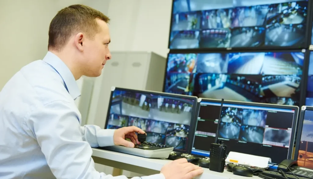 Security operator monitoring multiple surveillance screens in a control room.