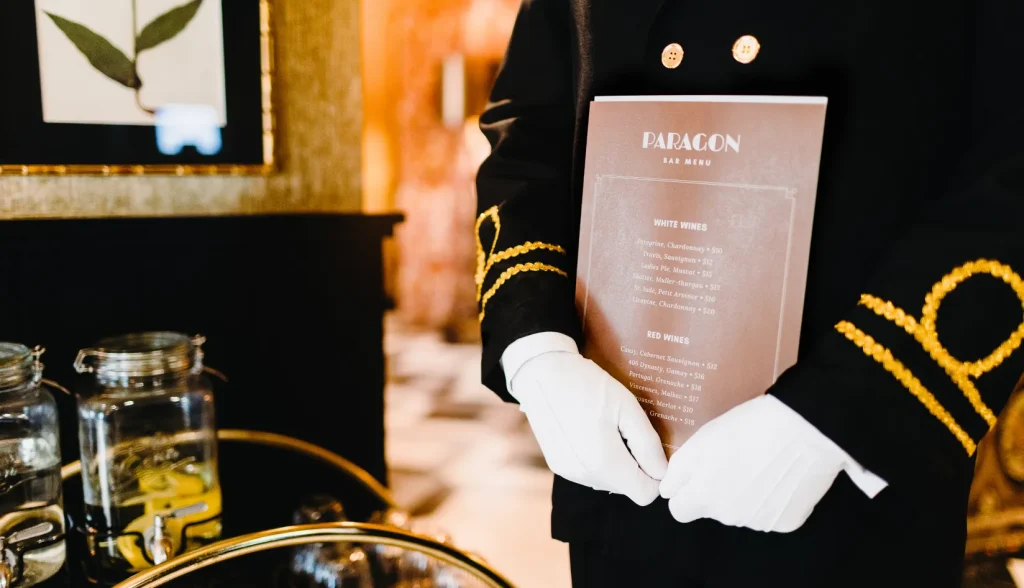 Hotel staff presenting a "Paragon Bar Menu"—reflecting the property’s upscale brand identity.