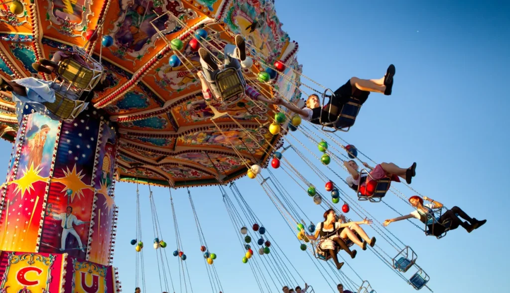 Visitors enjoying a swinging amusement ride, laughing and relaxing during their theme park experience.