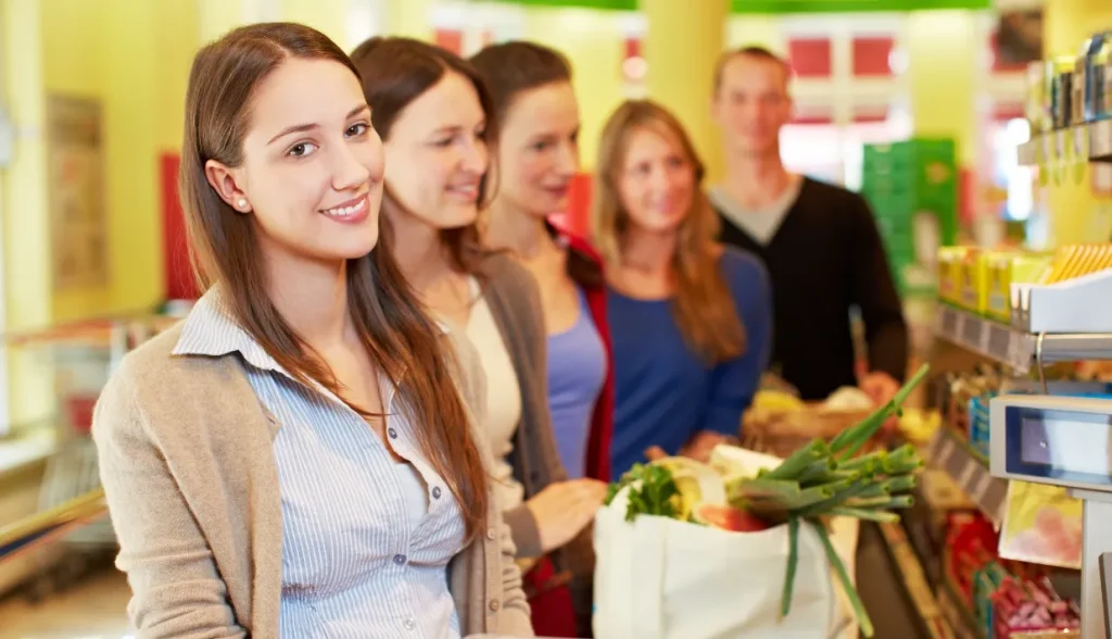 Group of smiling shoppers with a grocery bag in a retail store.