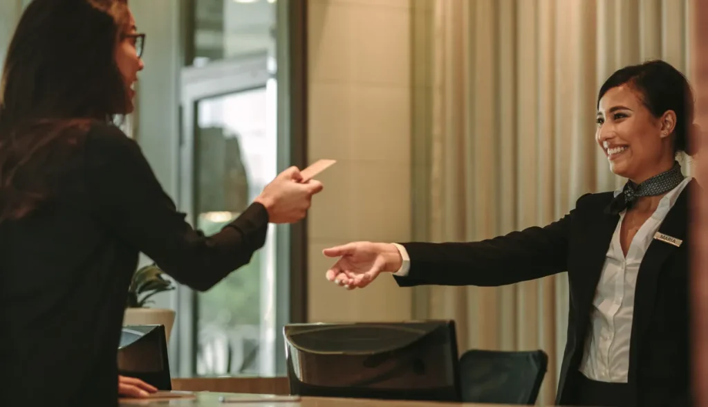 Hotel staff handing smart key card to guest with a smile.
