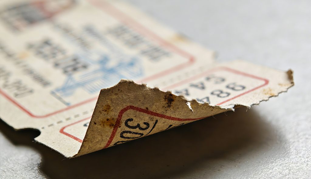 Worn, torn paper event ticket, contrasting with the durability and efficiency of RFID cards for large events.
