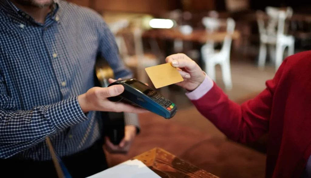 Person using a payment terminal to process an NFC card transaction, demonstrating why payment systems trust NXP NFC chips.
