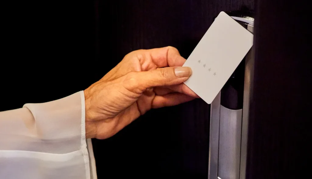 Person unlocking a hotel room door with an RFID key card.