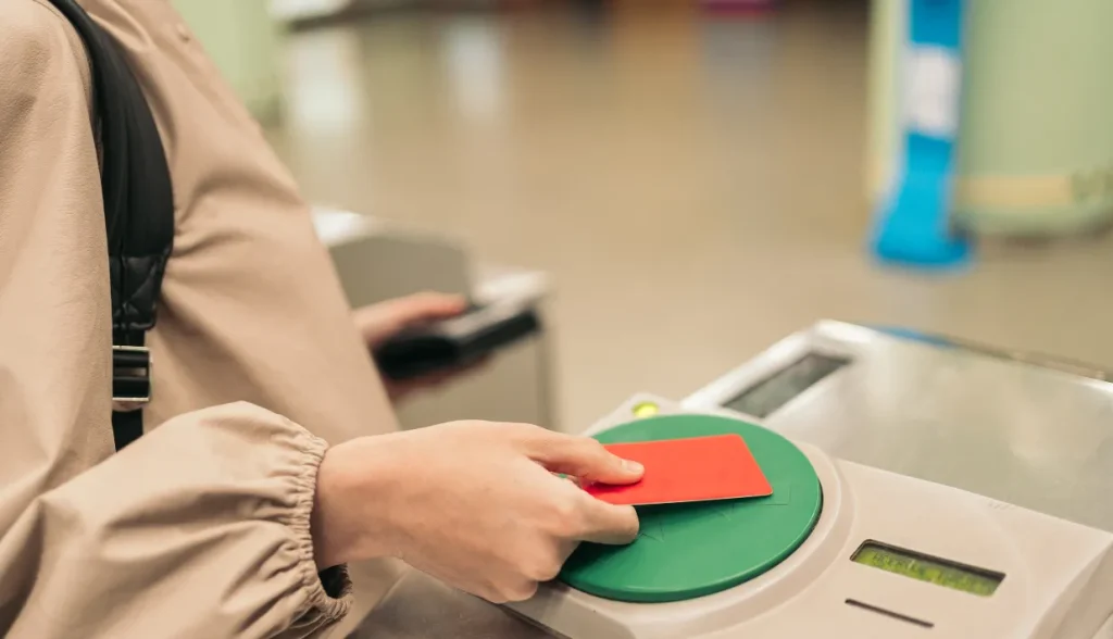 Passenger tapping a contactless card on a public transport ticket reader.