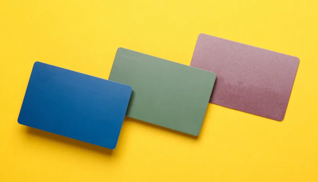 Three solid-colored blank RFID cards in blue, green, and purple on a yellow background.