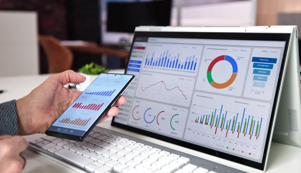 Person analyzing business analytics dashboards on a smartphone and a laptop.