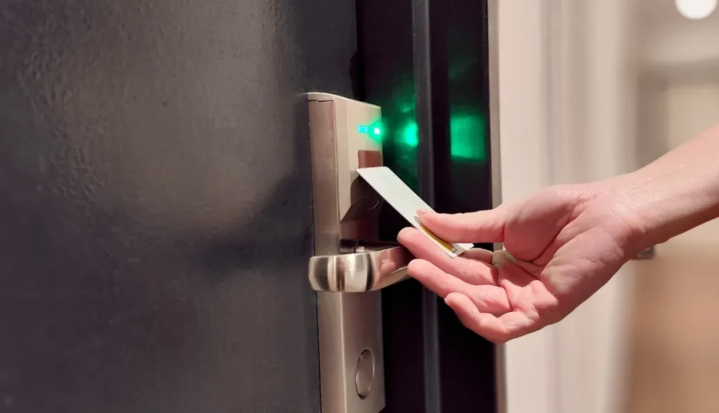 Hand inserting an RFID key card into a smart door lock with a green indicator light.
