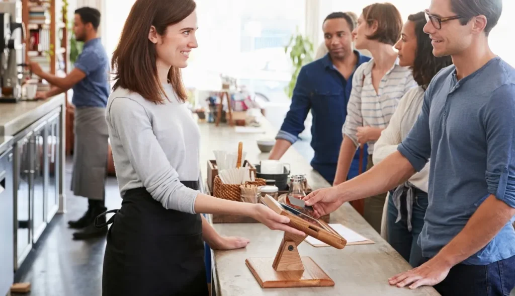 A customer using a contactless card at a cafe POS terminal, showing the widespread adoption of RFID payment technology in everyday retail.