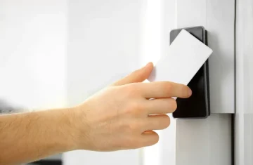 How to Choose the Right RFID ID Card for Access Control Systems A hand holding a blank white RFID card against an access control reader, illustrating basic card presentation for door entry.