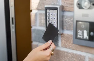 How to Implement an NFC Access Control System in Your Facility (Step- User swiping an NFC access card at a wall-mounted keypad access control reader outside a building entrance.