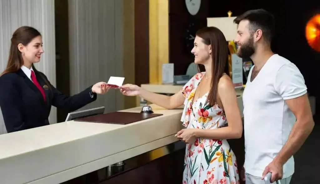 Hotel guest checking in at the front desk and receiving an RFID hotel key card for room access.