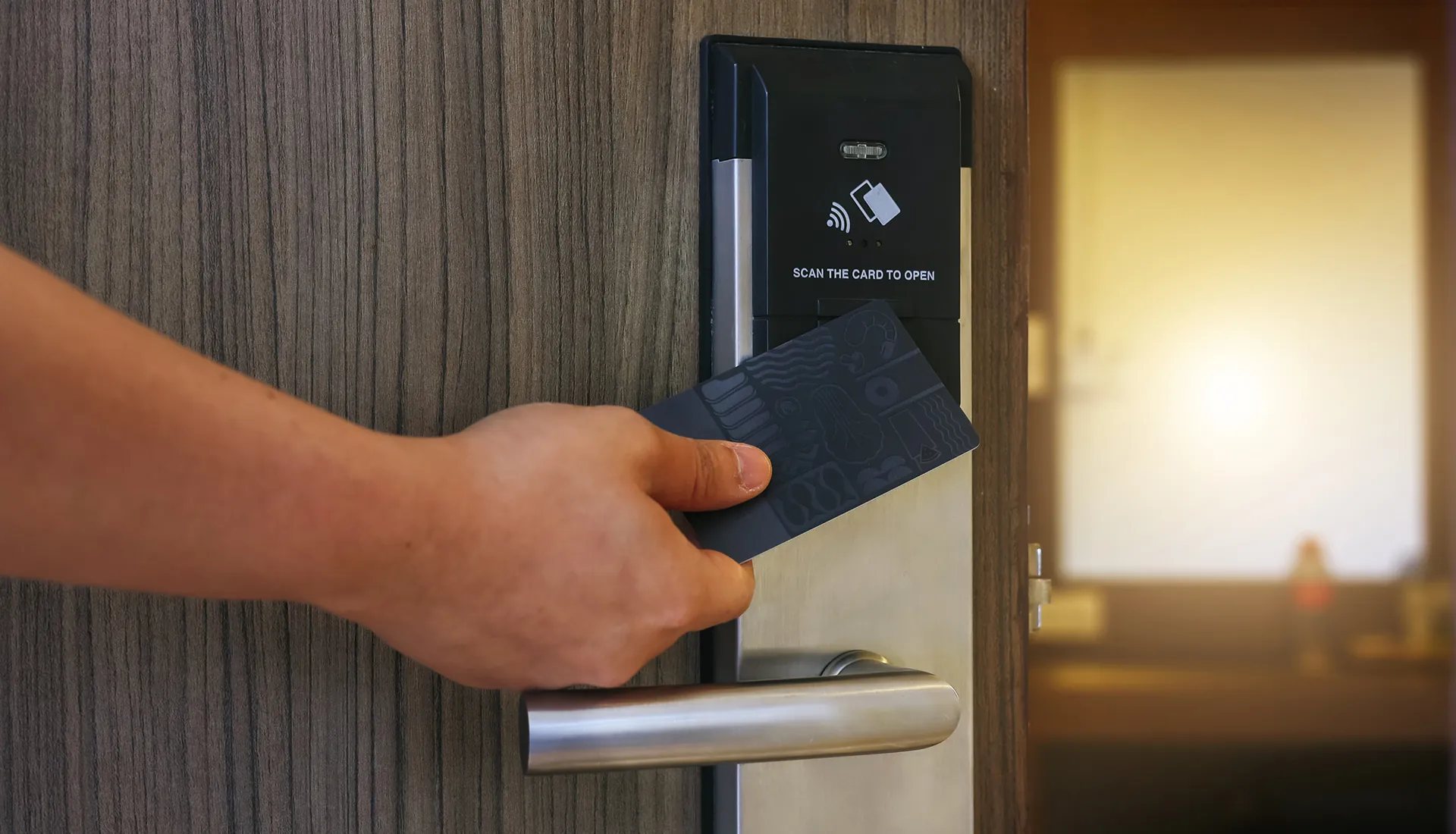 User holding a black smart card to scan and unlock at a modern electronic door lock induction area for contactless access control verification, demonstrating IoT high-security access control systems, smart hotel lock integration, and enterprise entry management.