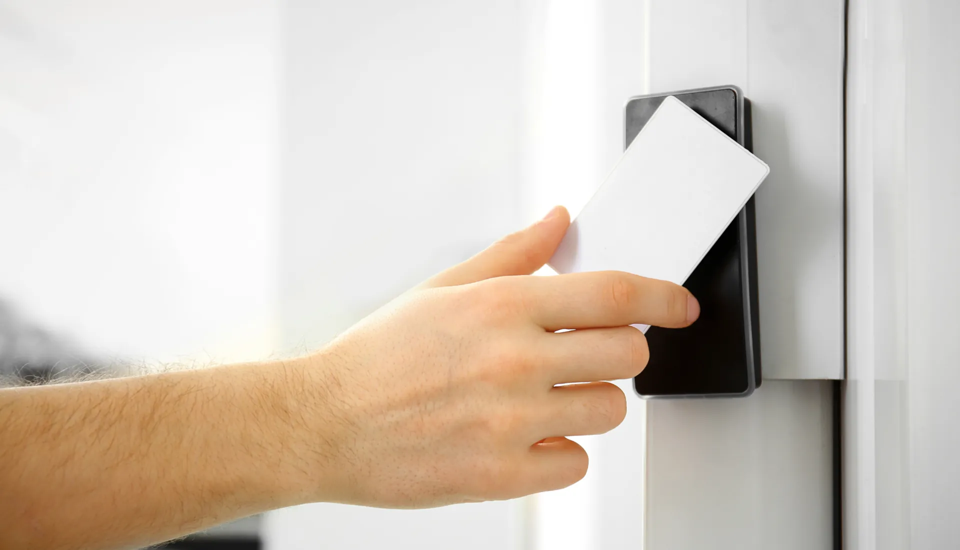 User holding a white smart card to scan and unlock at a modern electronic door lock induction area for standard room contactless verification, demonstrating IoT smart hotel access control systems, guest room entry management, and RFID key card practical application.